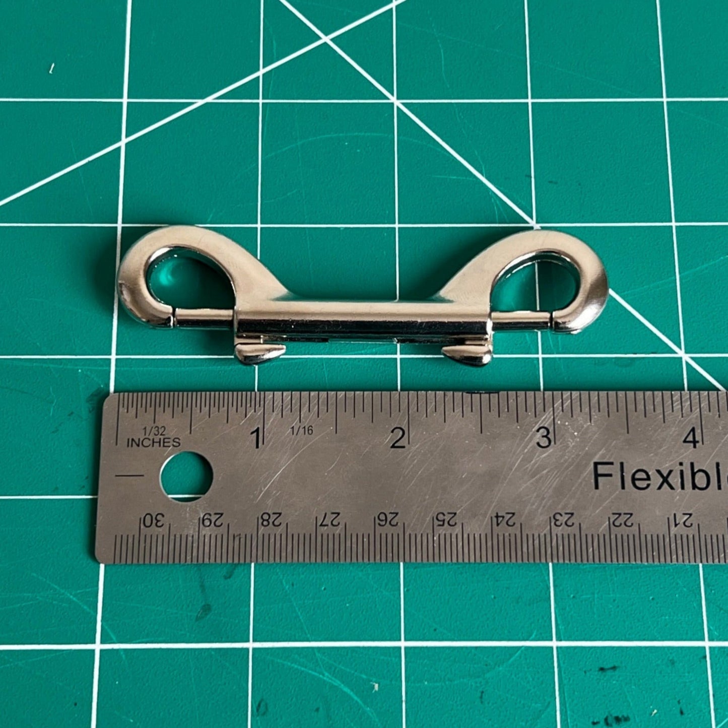 Metal clip on a green cutting mat with a ruler for scale