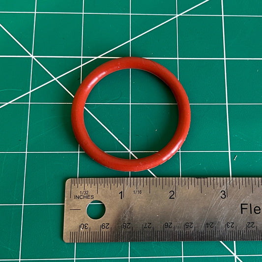 Red silicone O-ring on a green cutting mat with a ruler for scale.