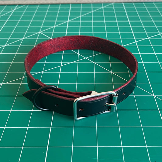 Red and black leather collar on a green cutting mat