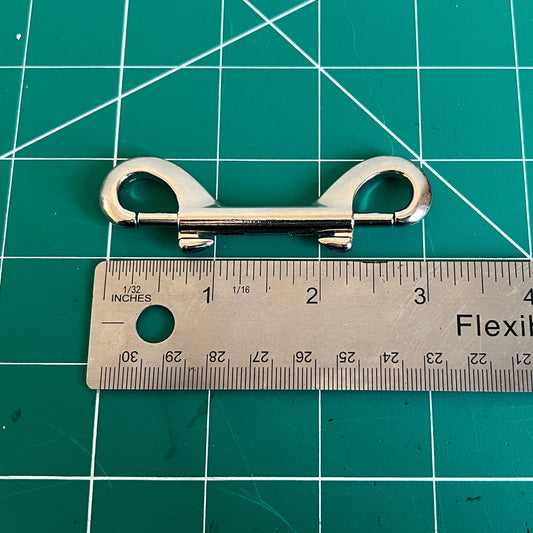 Metallic double ended clip on a green cutting mat with a ruler for scale.
